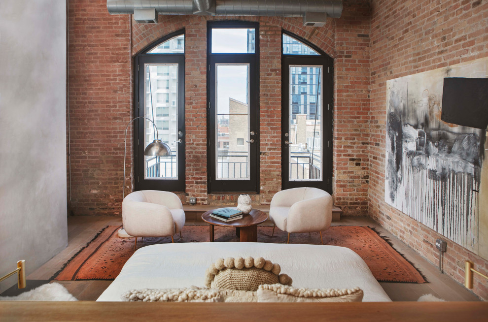 Modernes Hauptschlafzimmer mit hellem Holzboden, Kamin, verputzter Kaminumrandung, beigem Boden, freigelegten Dachbalken und Ziegelwänden in Chicago