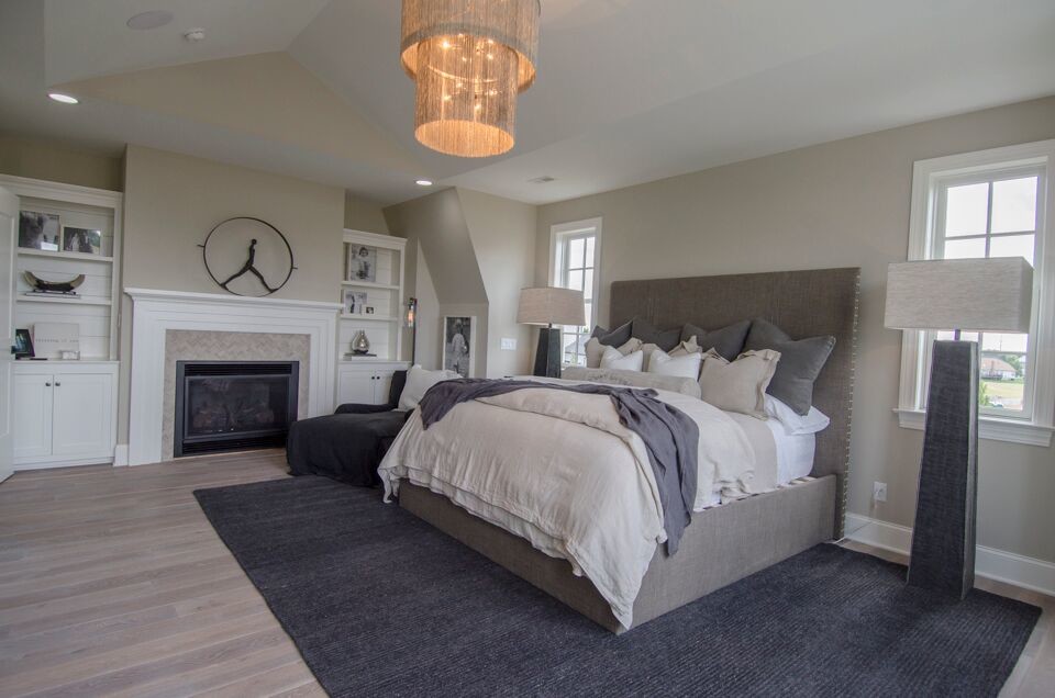 Large traditional master bedroom in Columbus with grey walls, light hardwood flooring, a standard fireplace, a stone fireplace surround and grey floors.