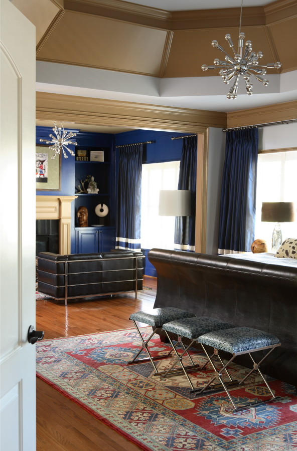 На фото: большая хозяйская спальня в стиле фьюжн с синими стенами, паркетным полом среднего тона, стандартным камином, фасадом камина из дерева и коричневым полом с
