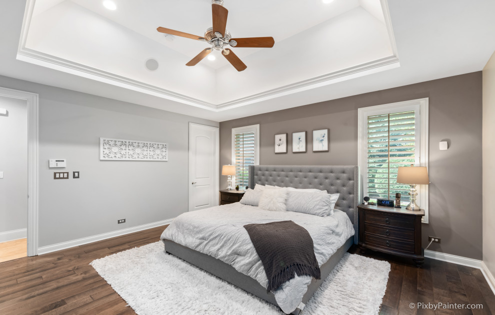 Großes Shabby-Look Hauptschlafzimmer mit grauer Wandfarbe, dunklem Holzboden, braunem Boden und eingelassener Decke