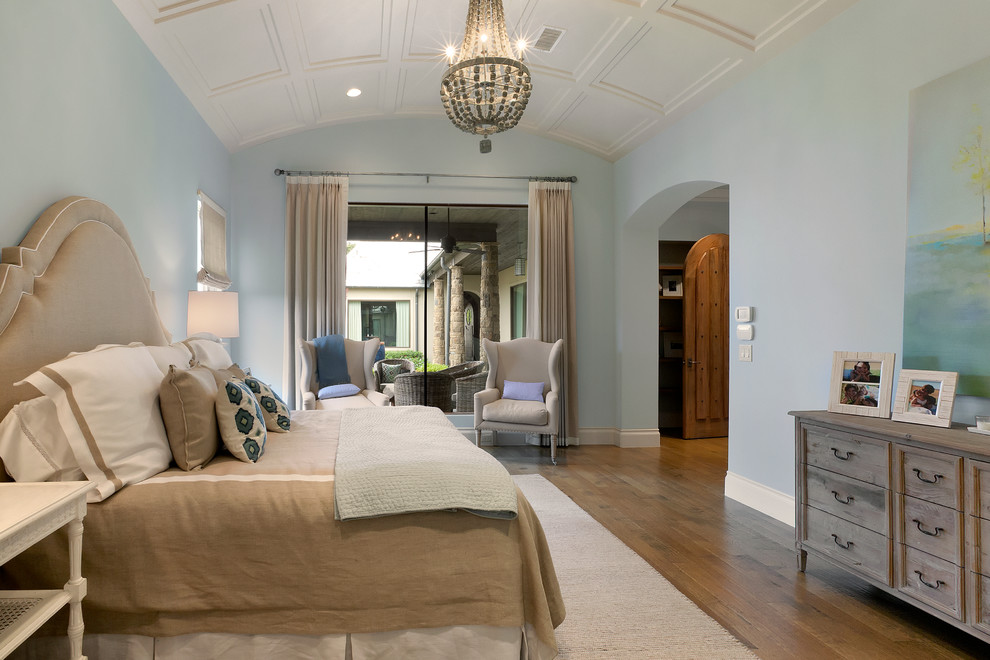 Modelo de dormitorio principal tradicional renovado extra grande sin chimenea con paredes azules y suelo de madera en tonos medios