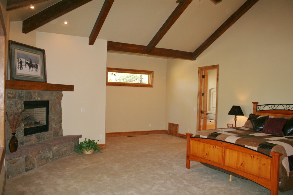 Diseño de dormitorio principal rural con moqueta, chimenea de esquina y marco de chimenea de piedra