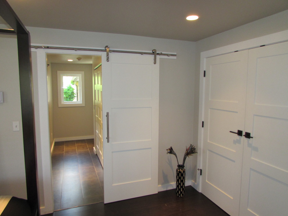 Idée de décoration pour une chambre parentale minimaliste de taille moyenne avec un mur gris et parquet foncé.
