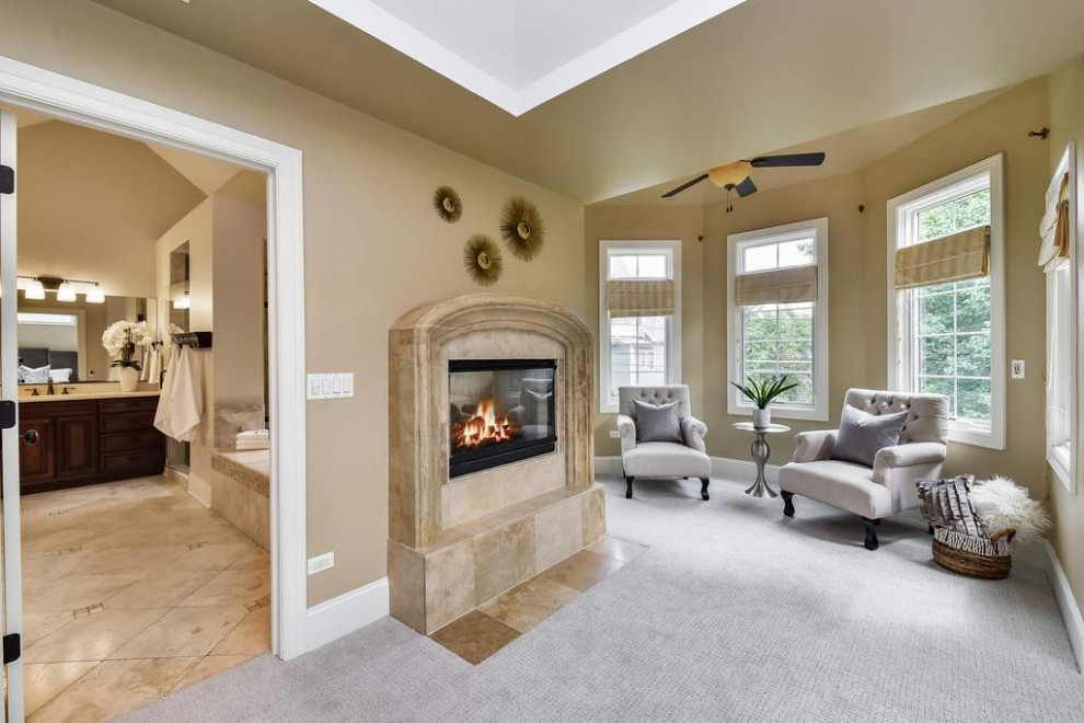 Photo of a large traditional master bedroom in Chicago with beige walls, carpet, a standard fireplace, a tiled fireplace surround, white floors and a vaulted ceiling.
