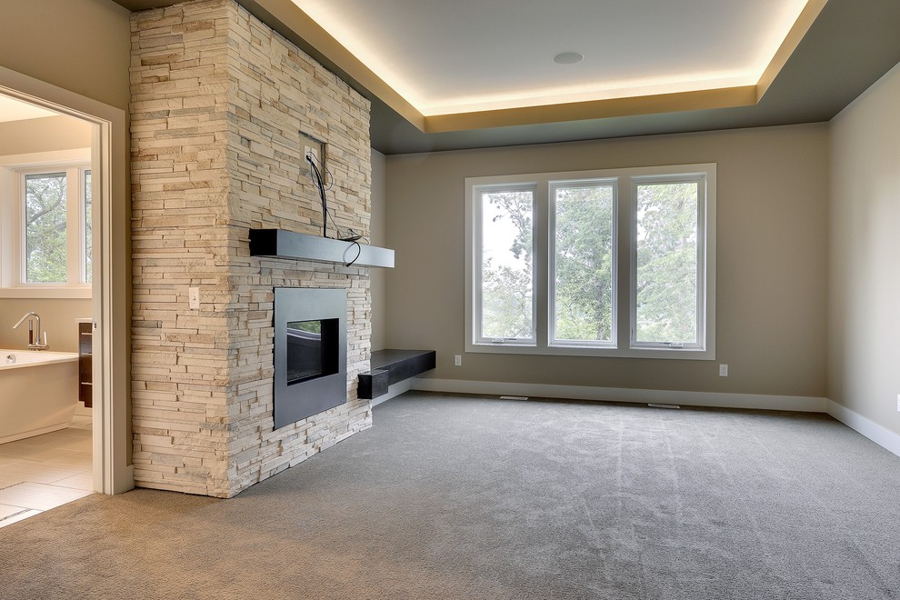 This is an example of a large traditional master bedroom in Minneapolis with beige walls, carpet, a standard fireplace and a stone fireplace surround.