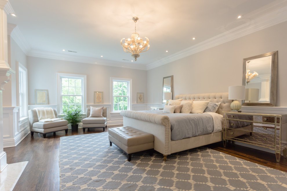 This is an example of an expansive classic master bedroom in New York with beige walls and medium hardwood flooring.