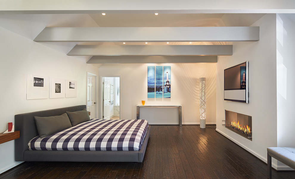 Ejemplo de dormitorio principal actual grande con paredes blancas, suelo de madera oscura y chimenea lineal