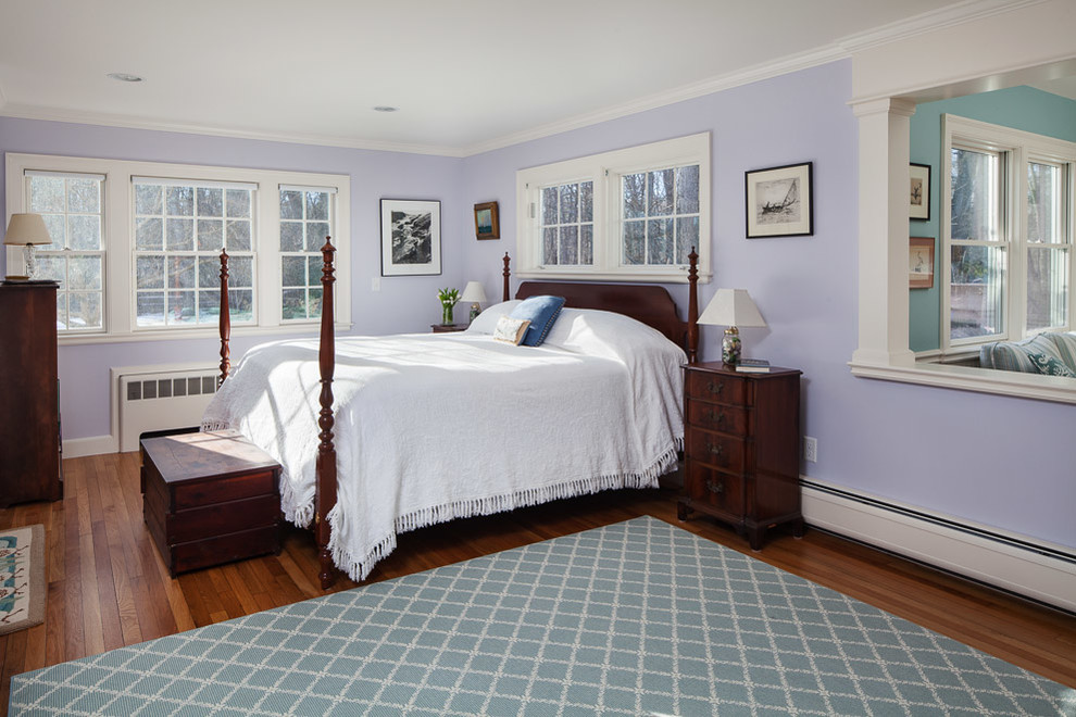 Modelo de dormitorio principal tradicional grande con paredes púrpuras, suelo de madera en tonos medios, todas las chimeneas y marco de chimenea de baldosas y/o azulejos