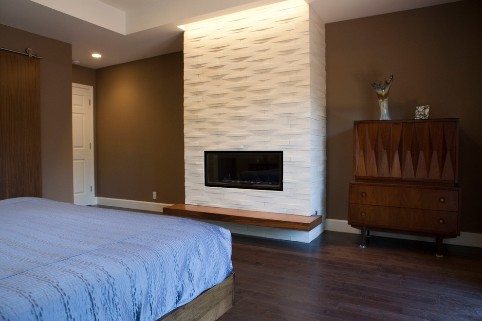 Cette image montre une grande chambre parentale minimaliste avec un mur marron, parquet foncé, une cheminée standard et un manteau de cheminée en carrelage.