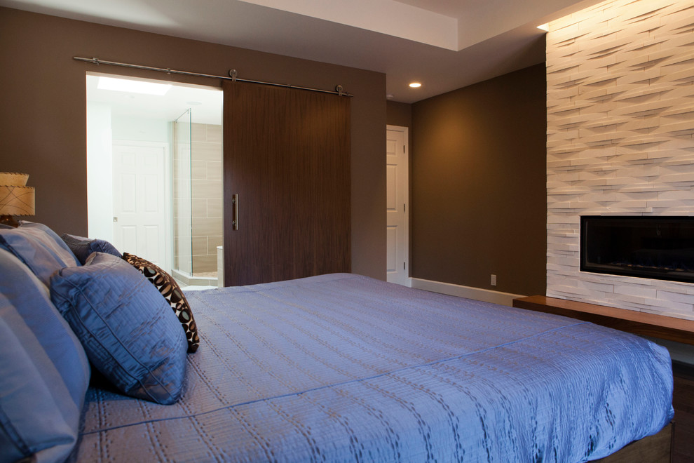 Cette image montre une grande chambre parentale minimaliste avec un mur marron, parquet foncé, un manteau de cheminée en carrelage et une cheminée ribbon.