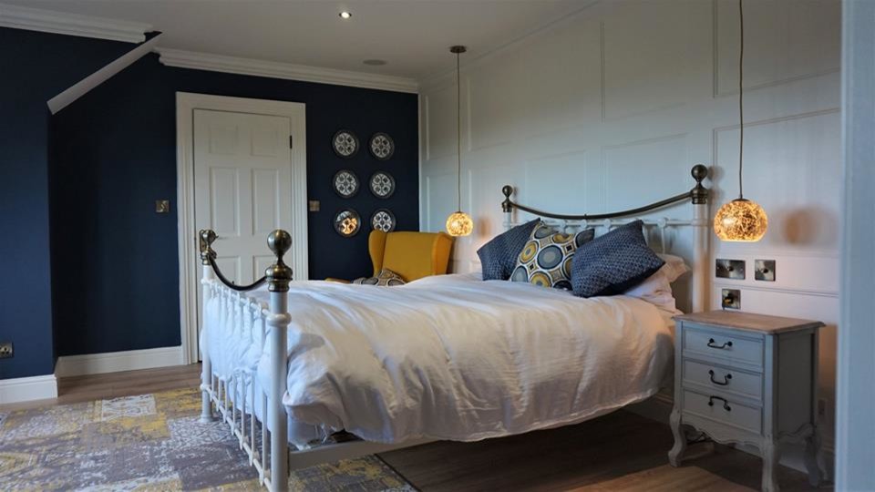 Immagine di una camera matrimoniale design di medie dimensioni con pareti blu, pavimento in laminato e pavimento marrone
