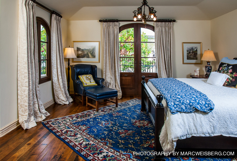 Modelo de habitación de invitados mediterránea grande sin chimenea con paredes blancas y suelo de madera en tonos medios