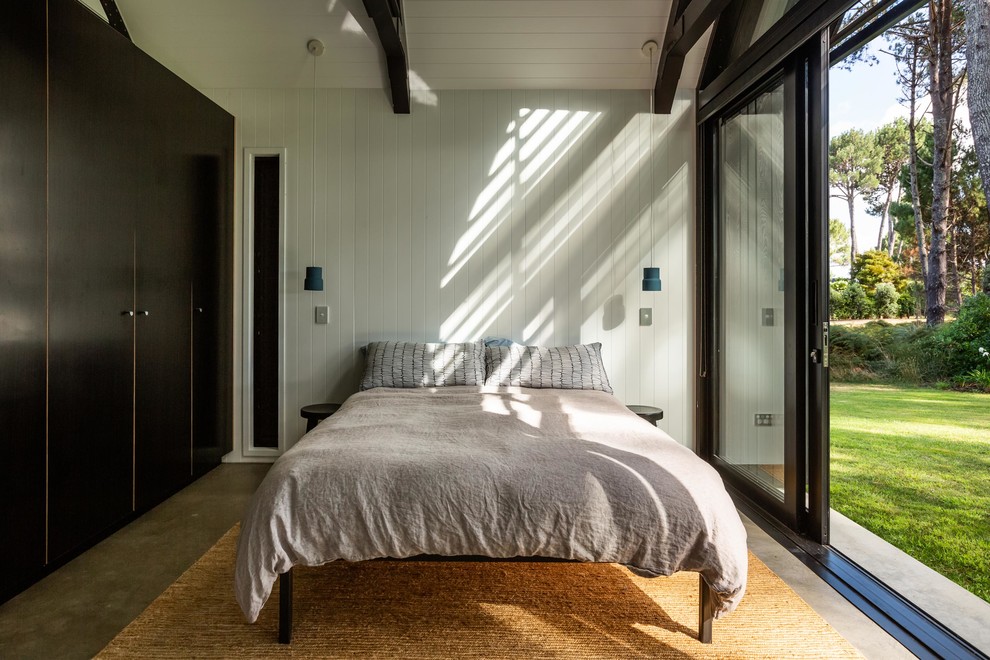 Modernes Schlafzimmer mit weißer Wandfarbe, Betonboden und grauem Boden in Auckland