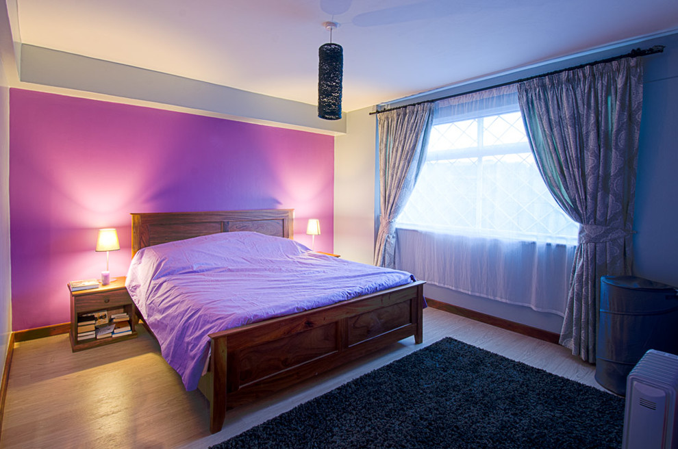 Diseño de dormitorio principal minimalista de tamaño medio con paredes púrpuras, suelo laminado y suelo marrón
