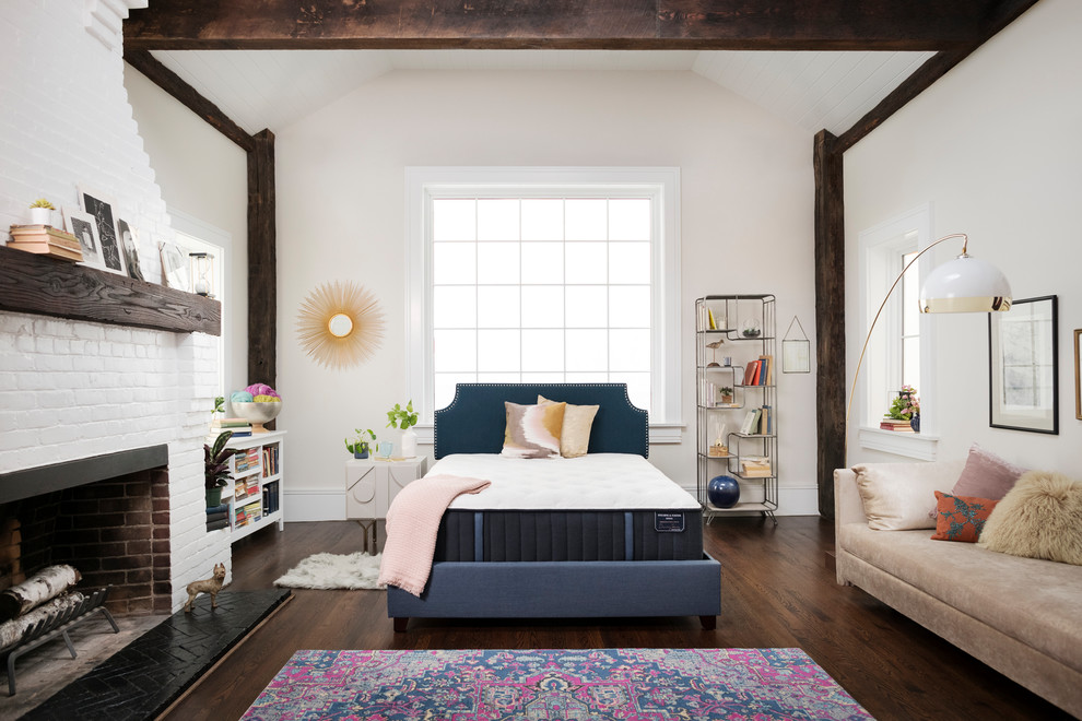 Design ideas for a medium sized farmhouse master bedroom in Other with white walls, dark hardwood flooring, a standard fireplace, a brick fireplace surround and brown floors.