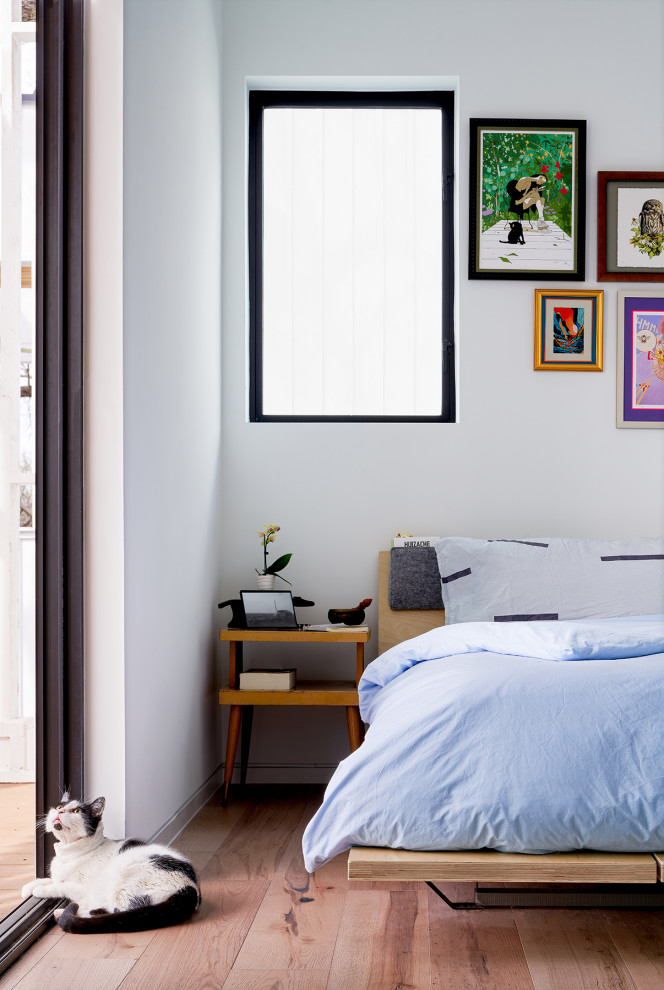 Kleines Mid-Century Schlafzimmer mit weißer Wandfarbe, braunem Holzboden und braunem Boden in Austin