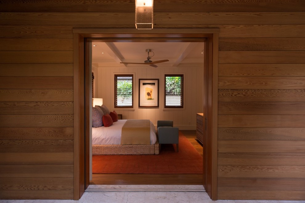 ハワイにある中くらいなトロピカルスタイルのおしゃれな客用寝室 (白い壁、無垢フローリング) のインテリア