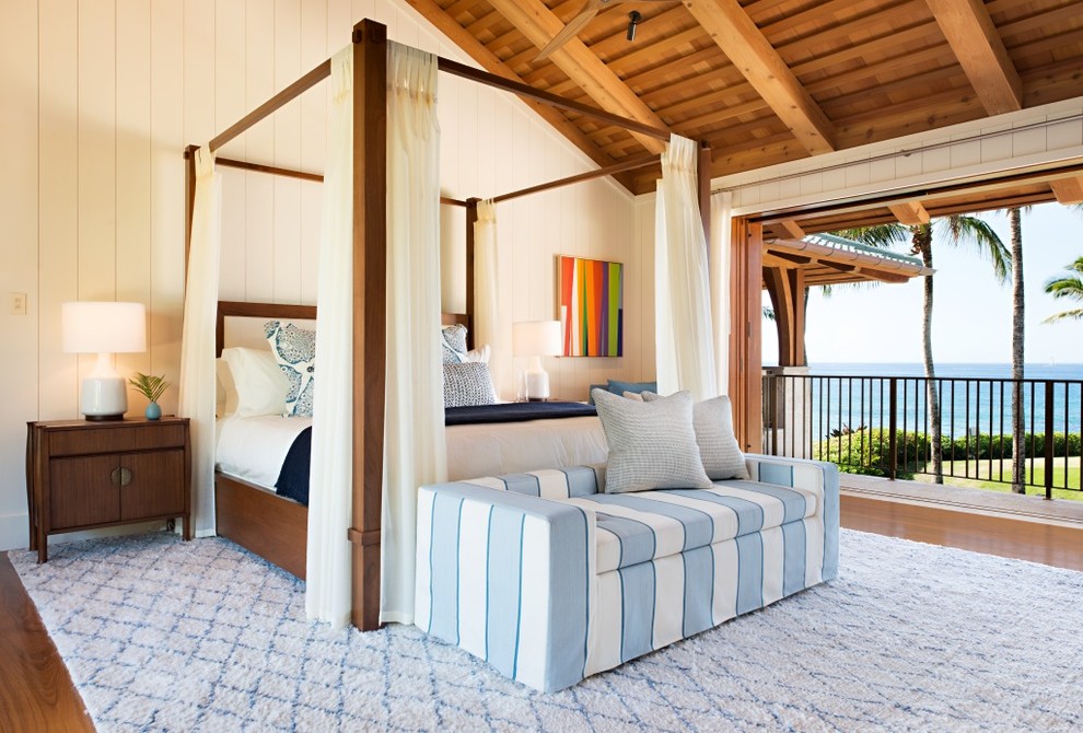 Ejemplo de dormitorio principal exótico grande sin chimenea con paredes blancas, suelo de madera en tonos medios y suelo marrón