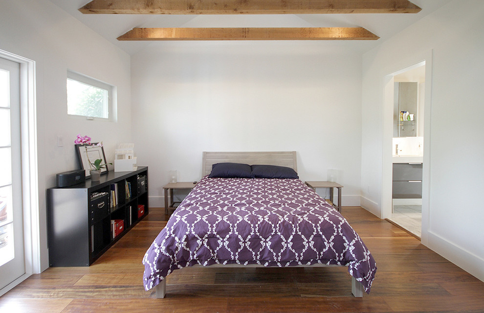 Aménagement d'une chambre contemporaine avec un mur blanc, un sol en bois brun et aucune cheminée.