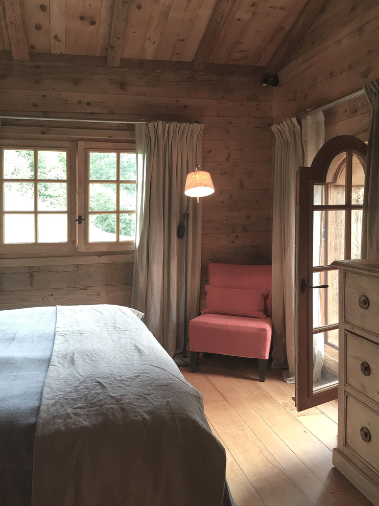 Modelo de dormitorio principal campestre de tamaño medio con suelo de madera clara