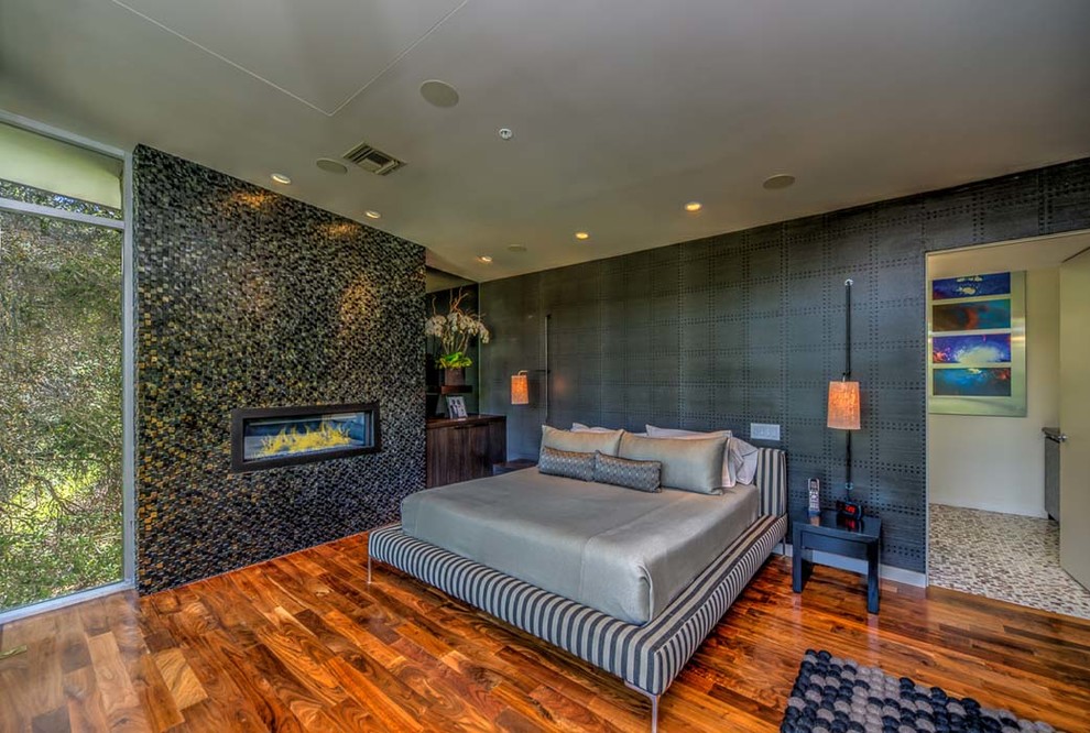 ロサンゼルスにある広いコンテンポラリースタイルのおしゃれな主寝室 (黒い壁、無垢フローリング、金属の暖炉まわり、横長型暖炉、茶色い床)