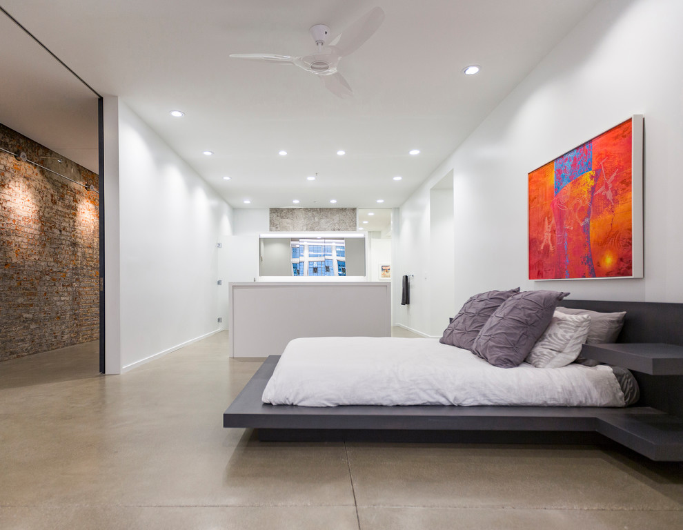 Esempio di una grande camera da letto stile loft industriale con pareti bianche, pavimento in cemento e pavimento grigio