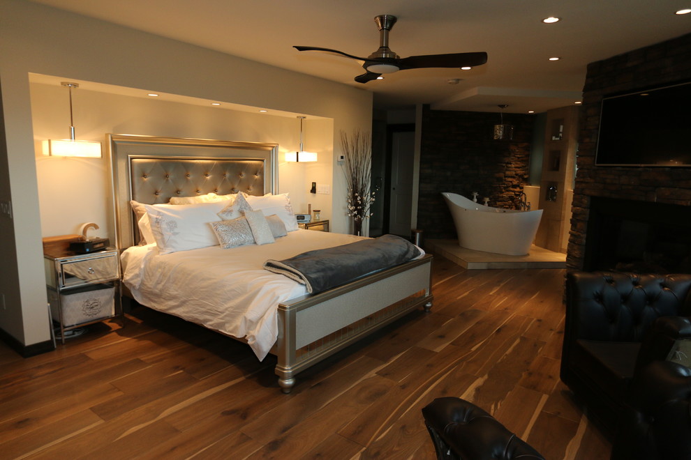 Geräumiges Rustikales Hauptschlafzimmer mit weißer Wandfarbe, hellem Holzboden, Eckkamin und Kaminumrandung aus Stein in Calgary