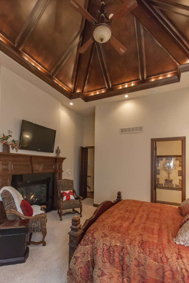Пример оригинального дизайна: большая хозяйская спальня в классическом стиле с бежевыми стенами, ковровым покрытием, стандартным камином и фасадом камина из дерева
