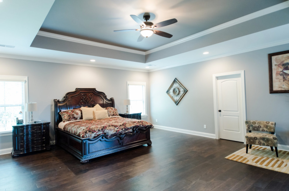 На фото: большая хозяйская спальня в классическом стиле с серыми стенами, темным паркетным полом и коричневым полом без камина
