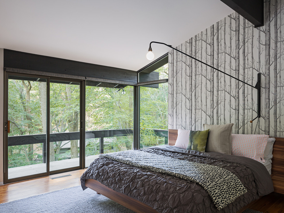 Immagine di una camera da letto minimalista con pareti multicolore e pavimento in legno massello medio