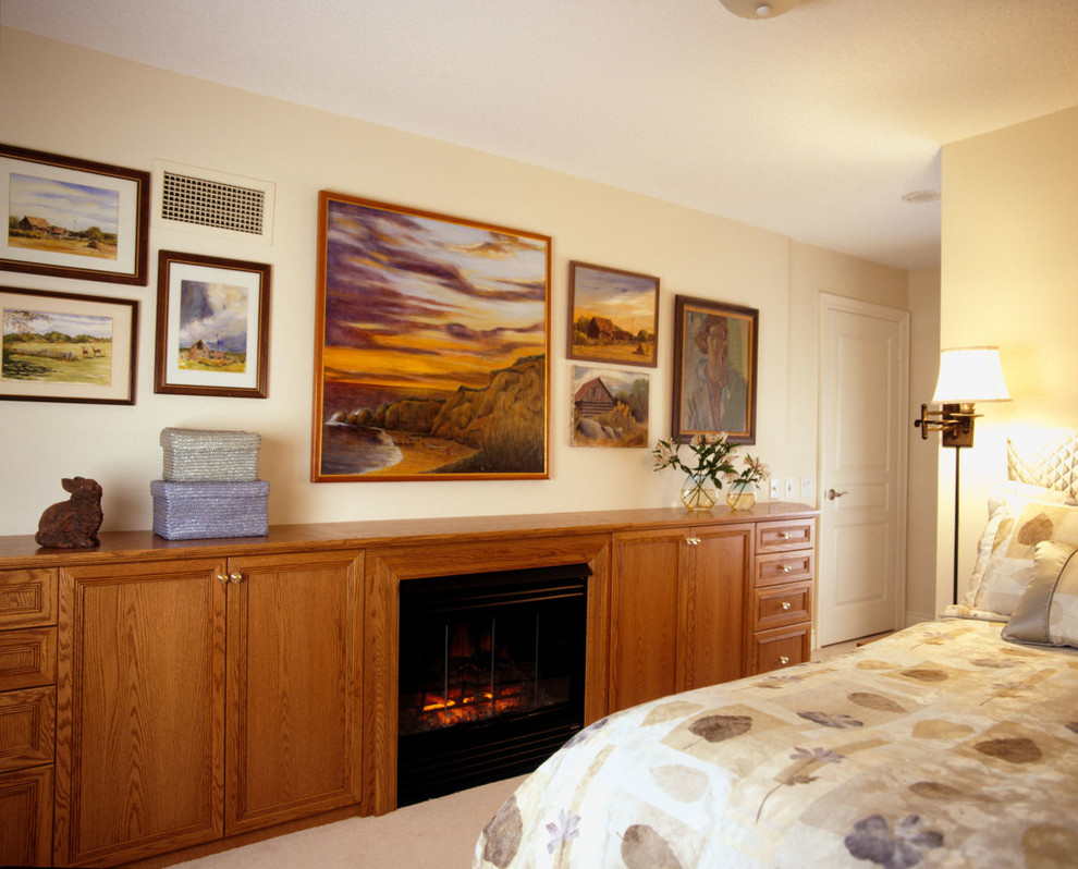 Ejemplo de dormitorio principal clásico pequeño con paredes amarillas, moqueta, todas las chimeneas y marco de chimenea de madera