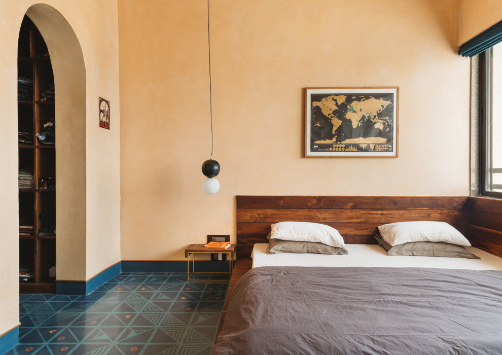 Immagine di una camera matrimoniale design con pareti arancioni, nessun camino e pavimento multicolore