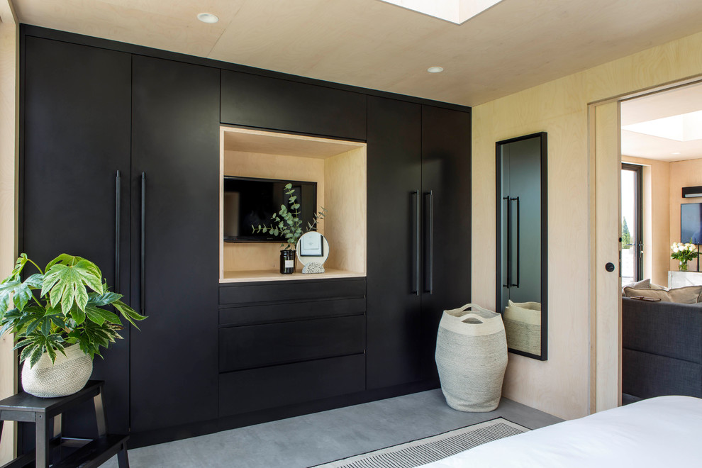 На фото: хозяйская спальня в скандинавском стиле с бежевыми стенами, бетонным полом, серым полом и телевизором без камина