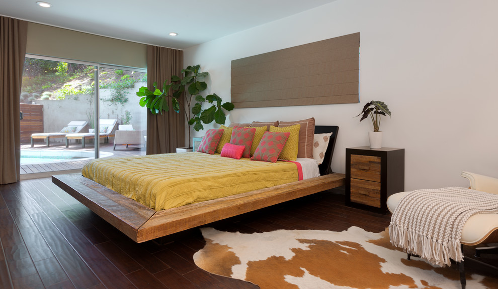 This is an example of a contemporary bedroom in Los Angeles with white walls and dark hardwood flooring.