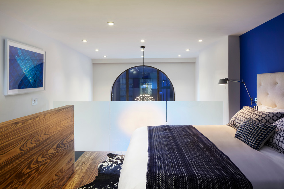 Imagen de dormitorio tipo loft contemporáneo pequeño con paredes azules y suelo de madera en tonos medios