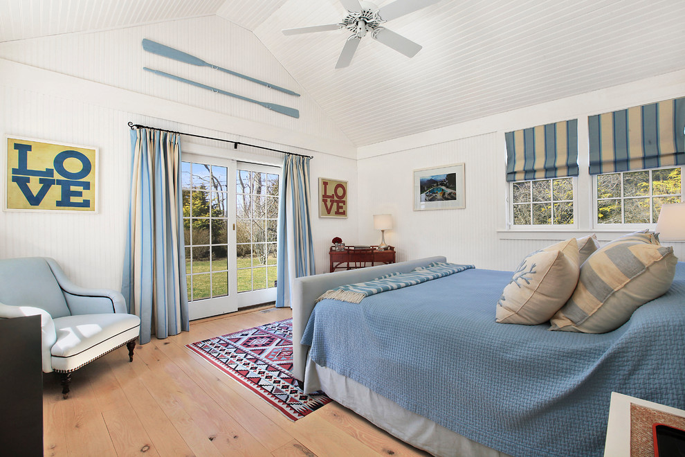 Example of a beach style medium tone wood floor bedroom design in New York with white walls