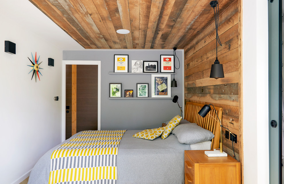 Cette photo montre une grande chambre parentale tendance avec un mur gris, parquet clair et un sol beige.
