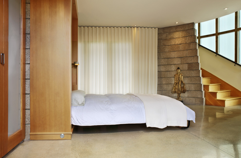 Foto di una camera da letto design con pareti beige e pavimento in cemento