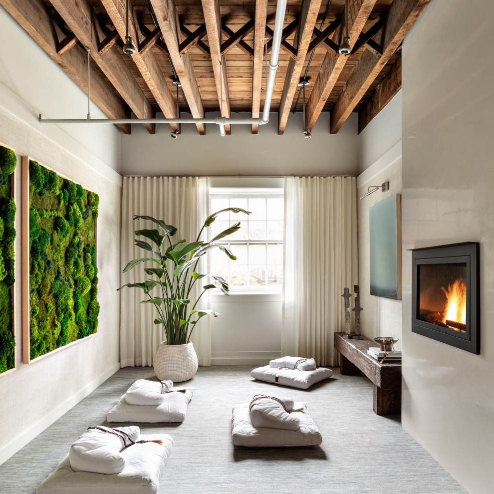 Example of a mid-sized trendy guest carpeted and blue floor bedroom design in New York with white walls, a hanging fireplace and a plaster fireplace