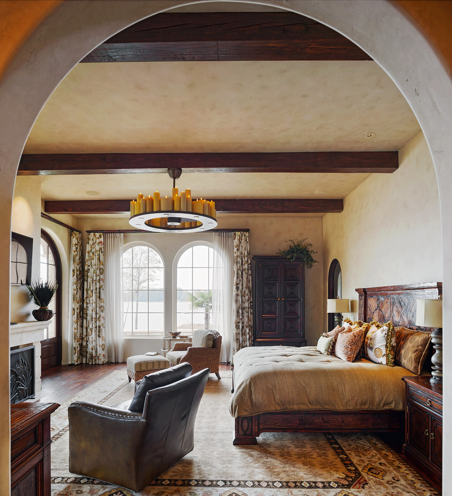 Bedroom - mediterranean dark wood floor bedroom idea in Other with beige walls and a standard fireplace