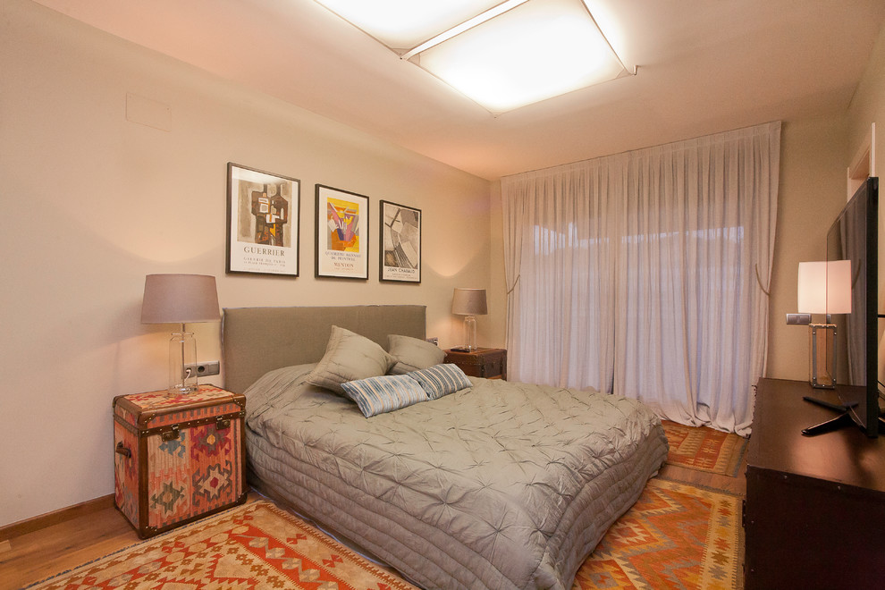Cette photo montre une chambre mansardée ou avec mezzanine tendance de taille moyenne avec un mur gris et un sol en bois brun.
