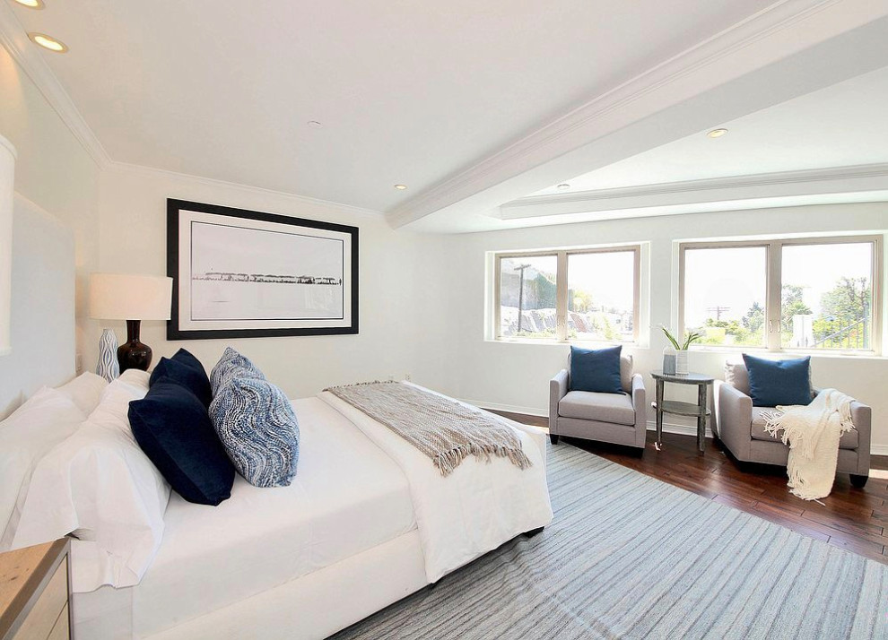 This is an example of a large mediterranean guest bedroom in Los Angeles with white walls, dark hardwood flooring, no fireplace, brown floors and a drop ceiling.