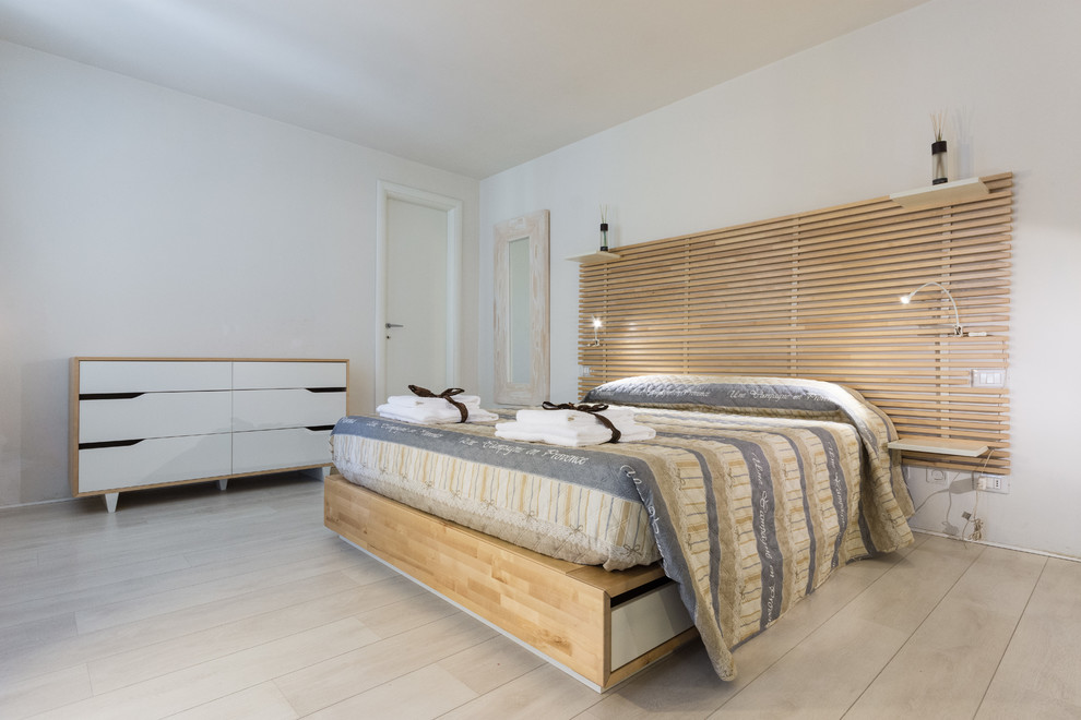 Modelo de dormitorio principal contemporáneo grande con paredes blancas y suelo de madera clara
