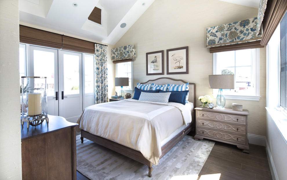 This is an example of a beach style master bedroom in Los Angeles with beige walls, medium hardwood flooring and brown floors.