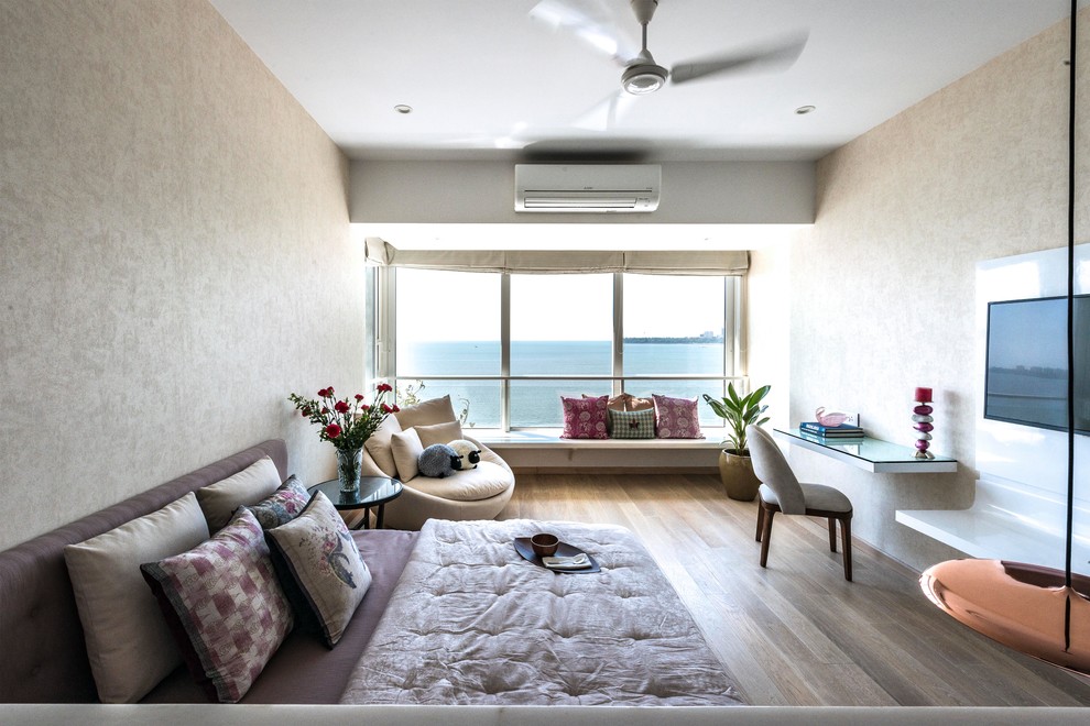 Asiatisches Hauptschlafzimmer mit beiger Wandfarbe, braunem Holzboden und braunem Boden in Mumbai
