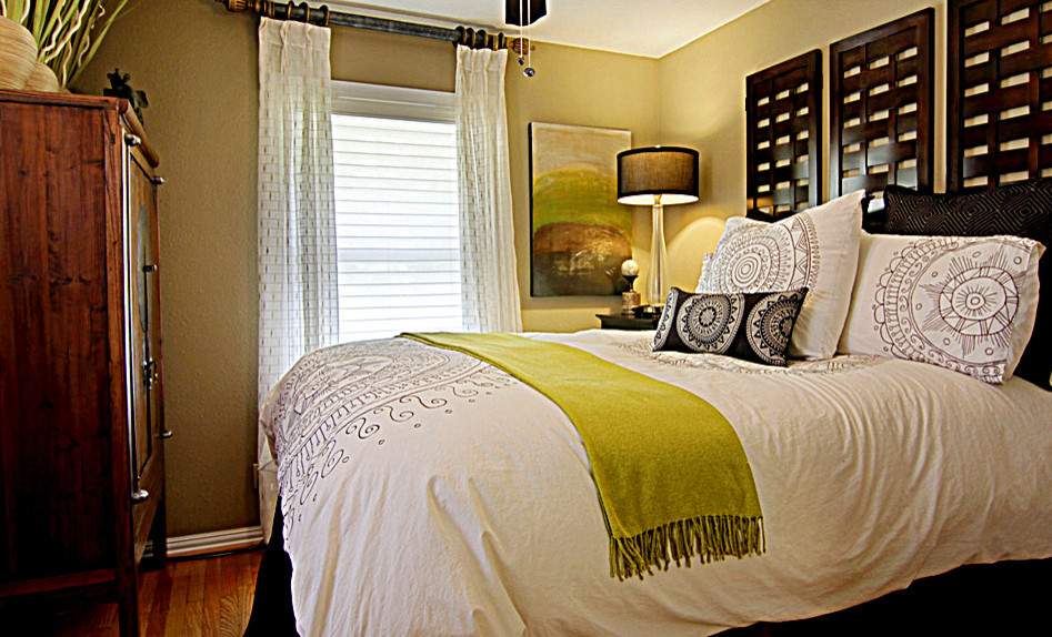 Geräumiges Modernes Gästezimmer mit gelber Wandfarbe und braunem Holzboden in Houston