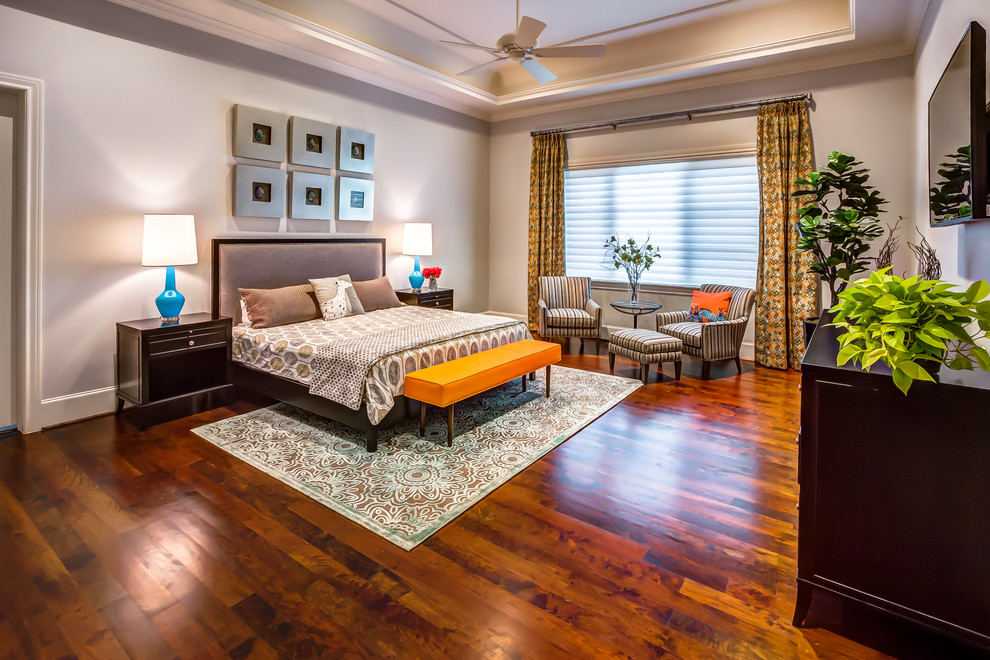 Modelo de dormitorio principal tradicional renovado grande con paredes grises, suelo de madera en tonos medios y suelo naranja