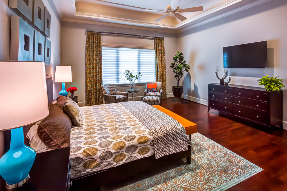Modelo de dormitorio principal tradicional renovado grande con paredes grises y suelo de madera en tonos medios