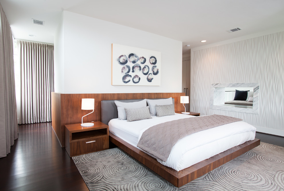Modernes Schlafzimmer mit weißer Wandfarbe, dunklem Holzboden und Tunnelkamin in Houston