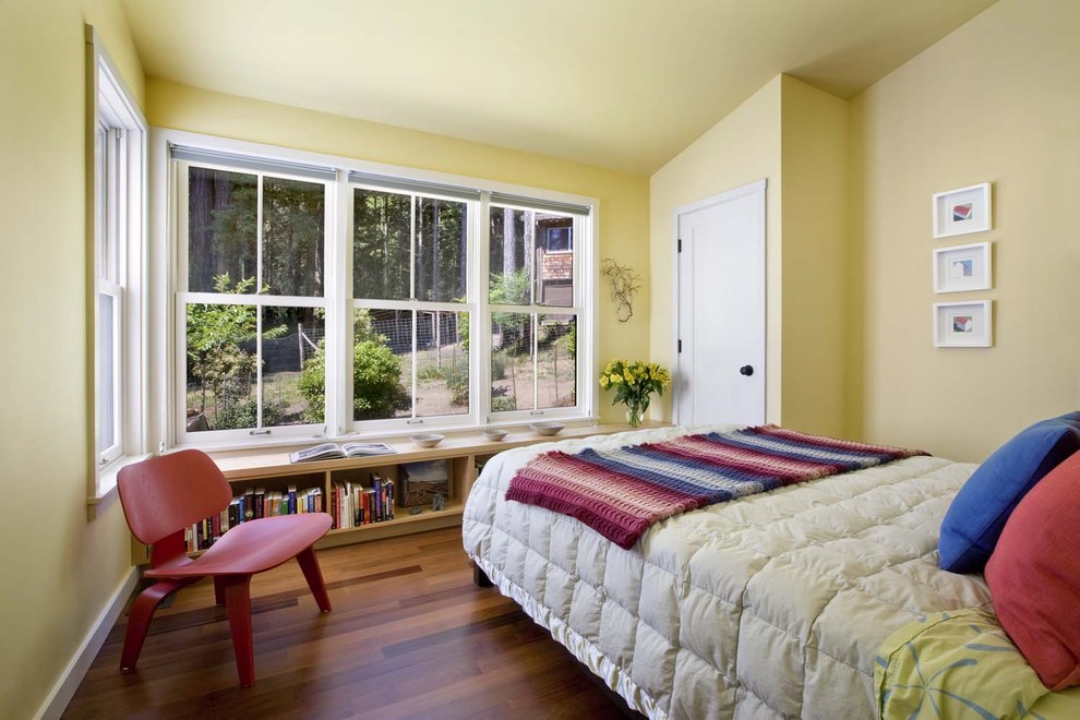 Idée de décoration pour une chambre chalet avec un mur jaune et un sol en bois brun.